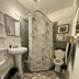 The Macaw Guesthouse bathroom in New York with shower, pedestal sink, toilet and patterned rug