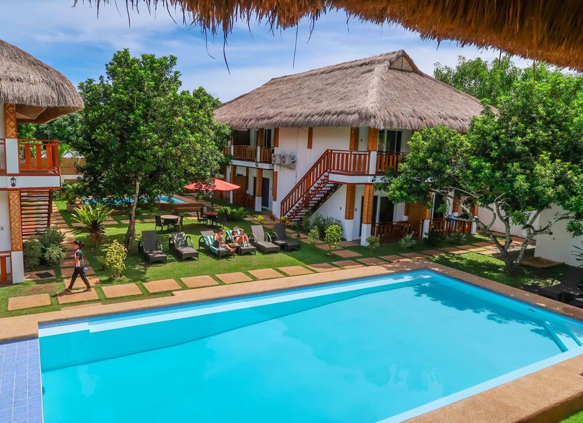 Scent of Green Papaya in Panglao with outdoor pool, lounge chairs, and thatched-roof villas