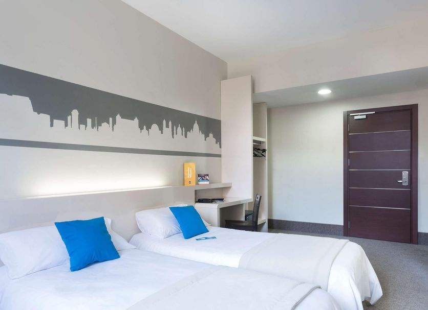 B&B Hotel Roma Trastevere room with twin beds, city skyline wall art, desk and wall-mounted TV in Rome