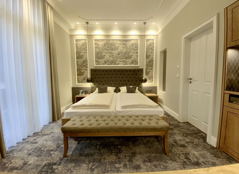 Hotel West an der Bockenheimer Warte room with twin beds, tufted bench and tall curtains in Frankfurt am Main