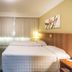 Tri Hotel Executive Caxias room in Caxias do Sul with two beds, TV, wardrobe and curtained window