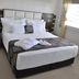 Orty Airport Hotel in Izmir guest room with neatly made bed, bedside lamps, and window blinds