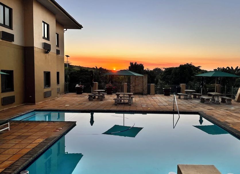 Hampshire Hotel - Ballito pool terrace at sunset with lounge chairs and picnic tables in Ballito