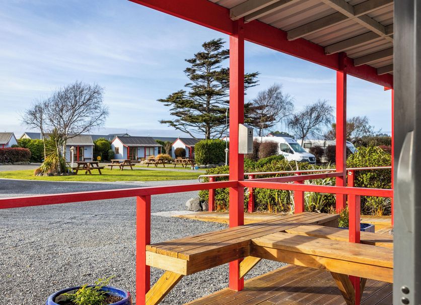 Kaikoura TOP 10 Holiday Park in Kaikoura: red-porch view of cabins, picnic tables and gravel grounds