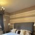 The Leather Bottle in Gravesend bedroom with patterned curtains, chandelier, and striped headboard