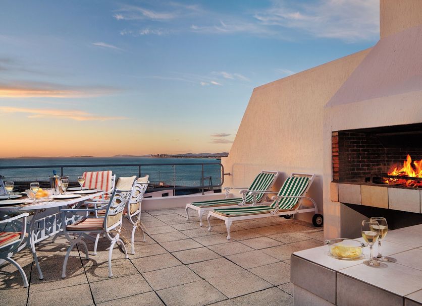 First Group Cape Gordonia rooftop terrace with sea view, lounge chairs, dining table and lit fireplace in Gordon's Bay