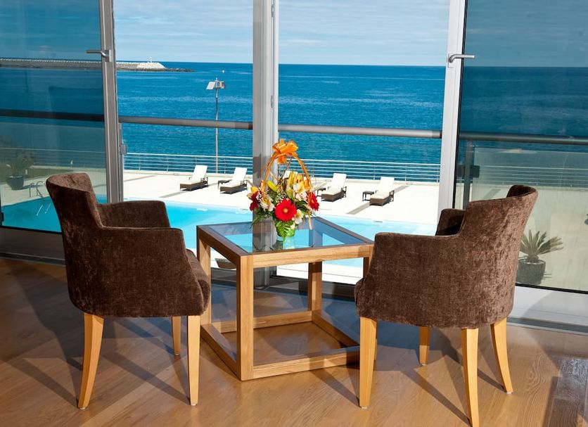 Atlantida Mar Hotel in Praia da Vitória: ocean-view lounge with table, chairs and flowers
