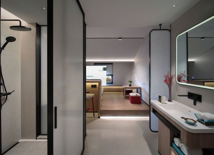 Ssaw Garden Hotel Beijing hallway leading to modern guest room with bathroom vanity and shower