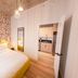The Laundry Rooms Augusta Hamilton in Hamilton: colorful bedroom with yellow bed, patterned accent wall, and kitchenette