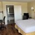 Hole Inn the Wall Hotel - Fort Walton Beach - Sunset Plaza room with bed, desk, chair and open bathroom door