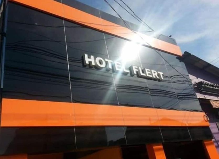Hotel Flert Santana in Sao Paulo exterior with black facade, orange accents, and sun glare