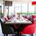 Bastion Hotel Barendrecht restaurant with long table, red chairs and large windows in Barendrecht