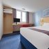 Travelodge Bedford Marston Moretaine room with double bed, desk, window and blue carpet in Bedford