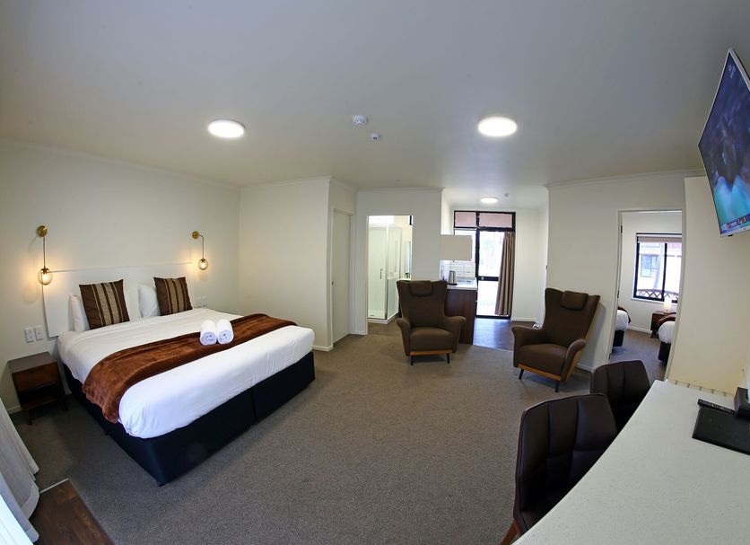 Heritage Court Motor lodge in Oamaru room with king bed, seating area, desk and wall-mounted TV