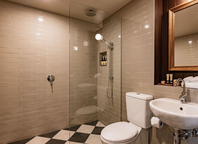 Hadley's Orient Hotel Hobart bathroom with walk-in shower, pedestal sink, toilet, and black-and-white tile floor