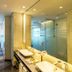 Vip Hotel Doha bathroom with double vanity, glass shower enclosure, and bedroom visible beyond