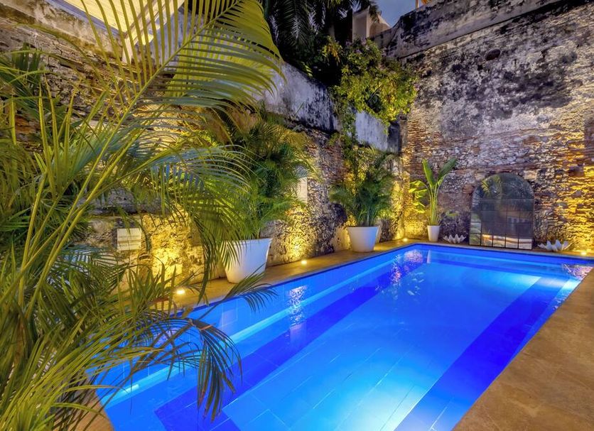 Hotel El Marqués by Faranda Boutique in Cartagena, stone courtyard with illuminated blue pool and tropical plants