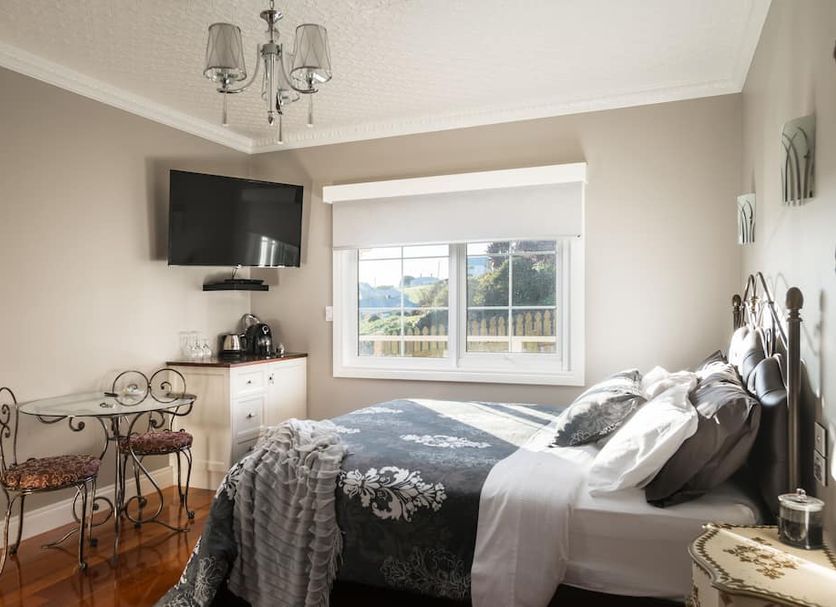 Noah's Stanley Luxury Bed and Breakfast guest room with bed, TV, small table, and window view in Stanley