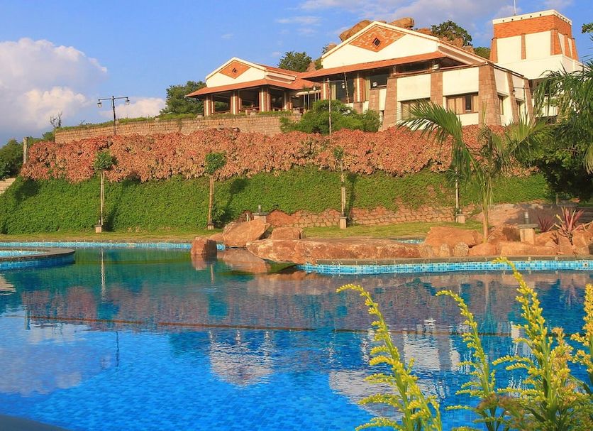 Kadambavanam Ethnic Village Resort in Madurai with hillside villas above a blue swimming pool