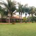Hillside Manor in Bulawayo with palm trees, a wide lawn, and a brick building exterior