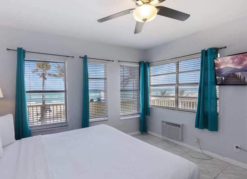 Paradise Oceanfront by Hbh in Hollywood bedroom with ocean views, turquoise curtains, and ceiling fan