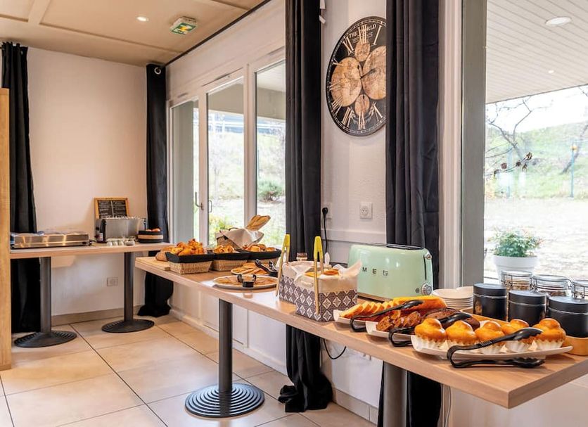 Kyriad Digne-Les-Bains breakfast buffet with pastries and drinks by large windows