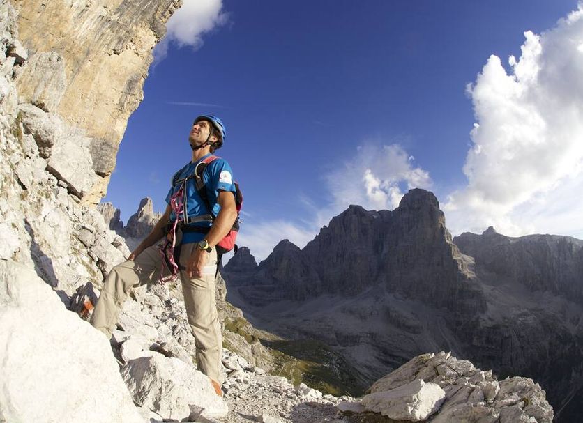 Dolomeet Boutique Hotel, Pinzolo: hiker on rocky cliff with dramatic mountain peaks under blue sky