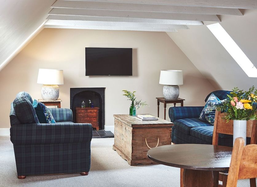 Brambles Of Inveraray attic lounge with plaid armchairs, fireplace, TV and skylight in Inveraray