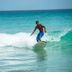 Melia Tortuga Beach in Santa Maria: surfer riding a wave with turquoise ocean and sailboat