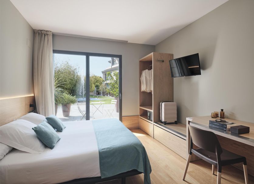 Qgat Restaurant Events & Hotel room with bed, desk, TV and sliding doors to garden in Sant Cugat del Vallès