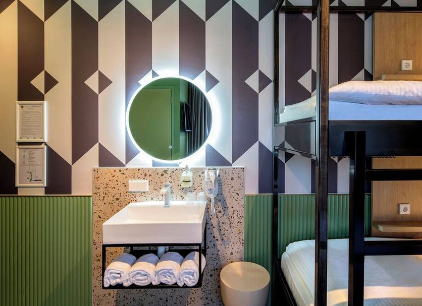 Tourist Inn One Amsterdam bathroom with glowing round mirror and bunk beds in Amsterdam