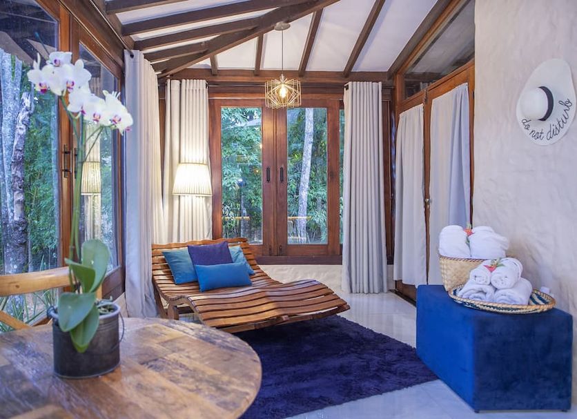 Pousada Cavaleiro Dos Pireneus room with wood-framed windows, lounge chair, and forest view in Pirenópolis