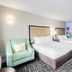 Clarion Pointe Winston - Salem Downtown guest room with two beds, mint chair and city mural in Winston-Salem