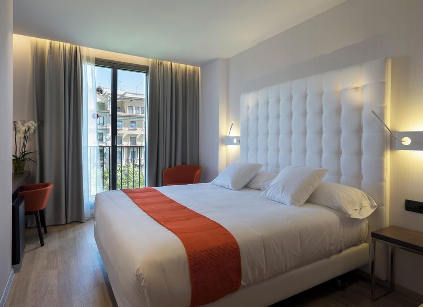 Chi Barcelona guest room with king bed, tufted headboard, balcony doors and city view