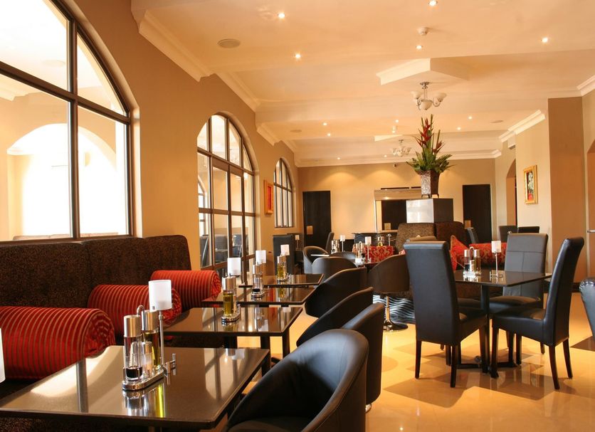 Velmore Hotel & Spa in Pretoria dining room with black tables, arched windows, and red banquettes