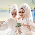 Bizotel Premier Hotel & Residence Bangkok: two guests in robes take a selfie with tea in a bright room