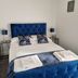OYO The Leven in Felixstowe bedroom with blue tufted bed and bedside lamps