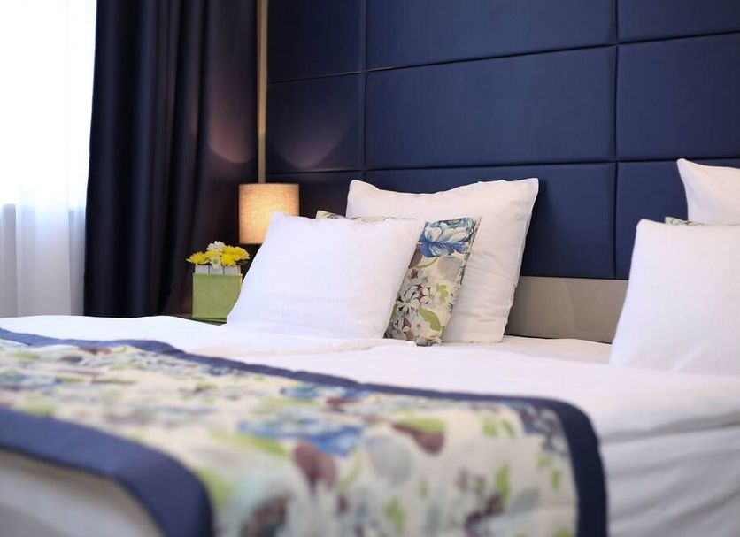 Old Town Hotel Sarajevo room with bed, dark paneled headboard, bedside lamp and window drapes