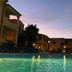 Residence Corte Dei Venti in Budoni with a lit outdoor pool at dusk and palm trees