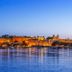 Taj Fateh Prakash Palace Udaipur lit up on the lakefront at dusk, reflecting on calm water