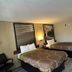 Super 8 by Wyndham Fayetteville guest room with two double beds, chair, and bathroom entrance