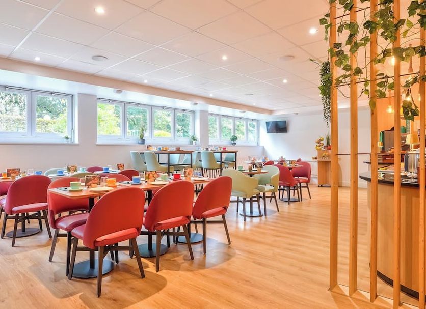 Residhome Bures La Guyonnerie breakfast room with red chairs and large windows in Bures-sur-Yvette
