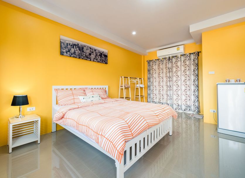 Sweet Dreams Phetchaburi guest room with double bed, bright yellow walls, mini fridge and window curtains
