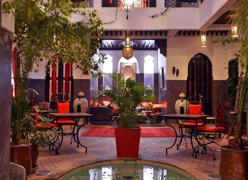Riad La Porte Rouge By La Siredrah in Marrakech courtyard with red seating and central potted plant
