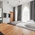 Piano Apartments Kaunas guest room with bed, wall-mounted TV, mirrored wardrobe, and tall windows