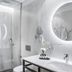Sofraga Palacio in Ávila bathroom with marble-look walls, glass shower, backlit round mirror and vanity