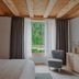 Aman Rosa Alpina guest room in Badia/Abtei with forest view, bed, window seating and wood ceiling
