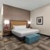 Hampton Inn & Suites Arroyo Grande/Pismo Beach Area guest room with king bed, teal chair, and ottomans