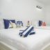 Casa Toñita in Levittown: bright white hotel room with two beds, nautical pillows, and folded towels