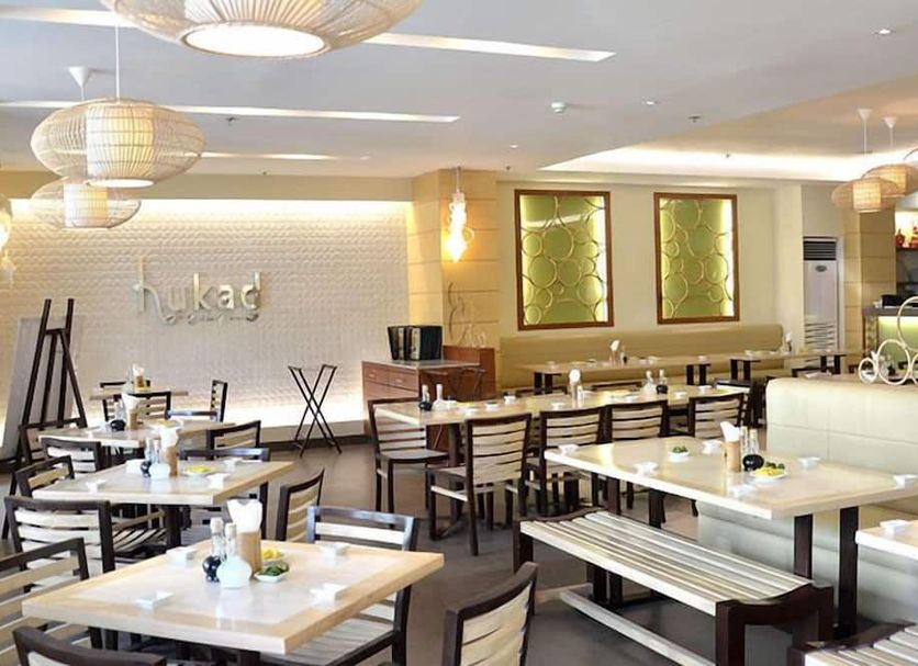 Royal Garden Hotel Ozamiz dining area with tables, benches, pendant lights and wall art